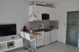 シッチェスにあるStudio Carrer de Valenciaの白いキャビネットと薄型テレビ付きのキッチンが備わります。