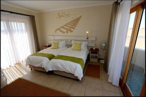 um quarto com uma grande cama branca com lençóis verdes em Stay @ Swakop em Swakopmund