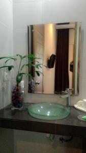 baño con lavabo verde y espejo en Kubu Carik, en Legian