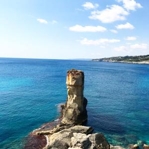 a rock formation in the middle of the ocean at Camping Porto Miggiano in Santa Cesarea Terme