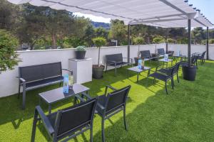 a grassy area with chairs, tables and umbrellas at GHT Sa Riera in Tossa de Mar