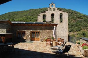 a stone building with a table and chairs and a clock tower at La Rectoria in Vall de Castellbò