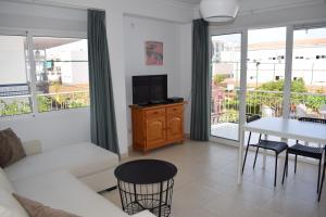 a living room with a white couch and a table with a tv at El Jardin BeNerja in Nerja