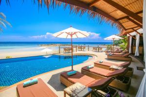 a pool with chairs and umbrellas next to the beach at Beyond The Blue Horizon Boutique Bungalows in Haad Chao Phao