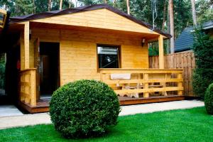 a small wooden cabin with a porch in a yard at Alkado Domki Jurata in Jurata