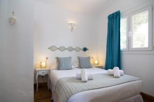 a bedroom with a large white bed with blue curtains at Wawa Tarifa in Tarifa