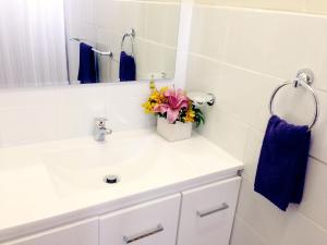 baño con lavabo blanco y toalla azul en Paradise Court Holiday Units en Airlie Beach