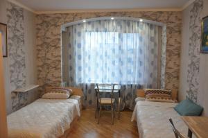 クラスノダールにあるApartment on Kubanka 3のベッドルーム1室(ベッド2台、テーブル、窓付)