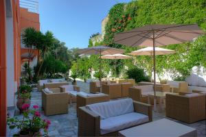 un patio con tavoli, sedie e ombrelloni di Hotel Benitses Arches a Benitses