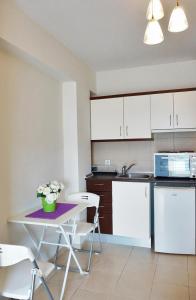a kitchen with white cabinets and a table with flowers on it at Ameris Studios & Apartments in Neos Marmaras