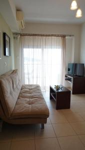 a living room with a couch and a large window at Ameris Studios & Apartments in Neos Marmaras
