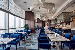 a restaurant with blue chairs and tables and windows at Minyoun Chengdu Dongda Hotel in Chengdu