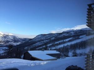 a view of a snow covered mountain with a barn at Skarsnuten Panorama 14 in Hemsedal