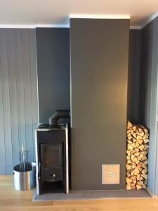 una estufa negra en una habitación con troncos en Skarsnuten Panorama 14, en Hemsedal
