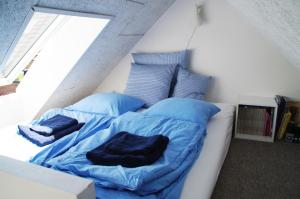 un letto con lenzuola e cuscini blu in una stanza di Aarhus bugtens Perle a Malling