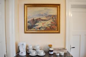 a painting on a wall above a table with cups at FE Gisting in Akureyri