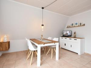 a dining room with a wooden table and white chairs at Finnhütte Carolin in Gager +4 photos