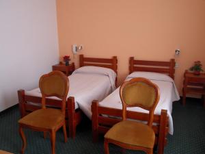 a room with two beds and two chairs at Albergo Betulla in Onore