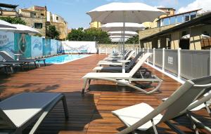 a row of lounge chairs and an umbrella on a deck at Best Western Hotel Anthurium in Santo Stefano al Mare
