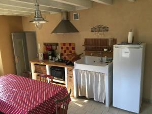 a kitchen with a table and a white refrigerator at Gite "Le Puy Rabasteau" in Chantonnay