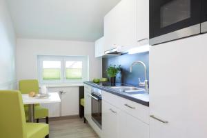 eine Küche mit weißen Schränken, einer Spüle und einem Tisch in der Unterkunft Good Rooms GmbH Bad Ischl in Bad Ischl