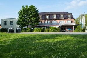 a building with a grass field in front of it at Hotel am See in Grevesmühlen