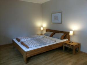 a bedroom with a large bed with two lamps at Appartements Fischerhus in Glowe