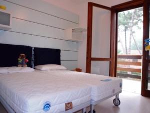 a bedroom with a white bed with a large window at Lignano Pineta very nice in Lignano Sabbiadoro