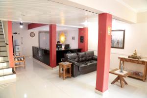 a living room with a black couch and red columns at Hotel Colonial in Pôrto Ferreira