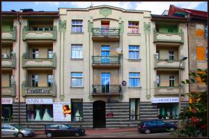 カトヴィツェにあるホステル カトヴィツェ セントラムのバルコニー付きの建物、車が正面に駐車しています。