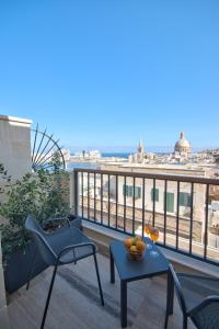 balcón con mesa, sillas y vistas a la ciudad en La Falconeria Hotel en La Valeta