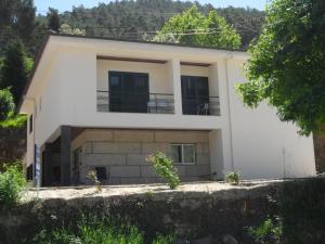 uma casa branca com uma varanda numa colina em Casa Da Veiga no Gerês