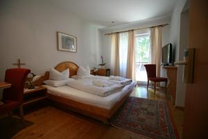 a bedroom with a bed with white sheets and a television at Bio-Hotel Saladina in Gaschurn