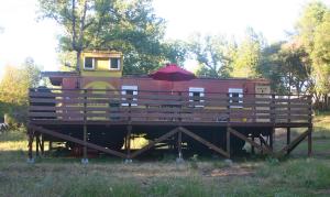 a red train car with an umbrella on a platform at Little Red Caboose in Oakhurst