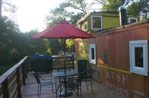 a deck with a table and chairs and an umbrella at Little Red Caboose in Oakhurst