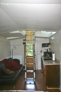 a living room with a ladder in a tiny house at Little Red Caboose in Oakhurst
