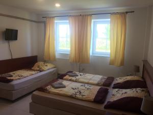 2 Betten in einem Zimmer mit 2 Fenstern in der Unterkunft Ubytovna Statek Olomouc in Olomouc