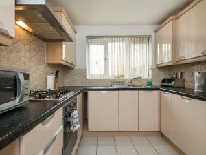 une cuisine avec des armoires blanches et un micro-ondes dans l'établissement My-Places Corporate Serviced Accommodation, à Manchester