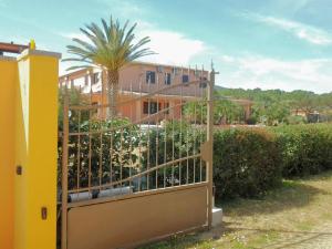 a gate in front of a building with a palm tree at Hotel Su Giudeu in Chia
