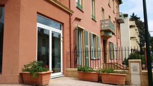 a pink building with potted plants in front of it at Hotel Marcellin in Beaulieu-sur-Mer