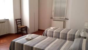 una camera con due letti e una sedia e una finestra di Da Iole a La Spezia