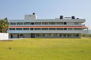een gebouw met een grasveld ervoor bij RNS Golf Resort & Nature Cure Centre in Māvalli