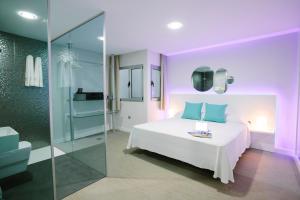 1 dormitorio con cama blanca y ducha acristalada en Valentina Beach, en Las Palmas de Gran Canaria