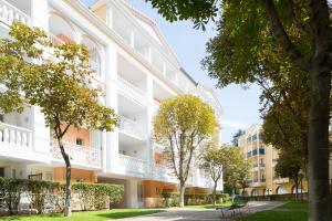 a white building with trees in front of it at Résidence du Bois de Lon in Lamalou-les-Bains