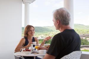 mężczyzna i kobieta siedzący przy stole z jedzeniem w obiekcie Résidence du Bois de Lon w mieście Lamalou-les-Bains