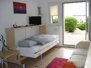 1 dormitorio con 1 cama, TV y ventana en Ferienwohnung Lenggenhager Plantzette en Sierre