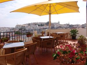 アルブフェイラにあるApartamentos Turisticos Reginaのパティオ(テーブル、椅子、黄色の傘付)