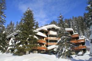 a building covered in snow with a tree in front of it at Alpen Appartements in Zauchensee