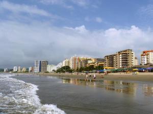 a beach with people walking on the sand and buildings at Apartamento de Lujo en Tonsupa in Tonsupa