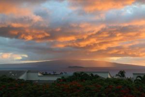 a sunset with a view of the ocean and mountains at Wailea Ekolu #607 in Wailea